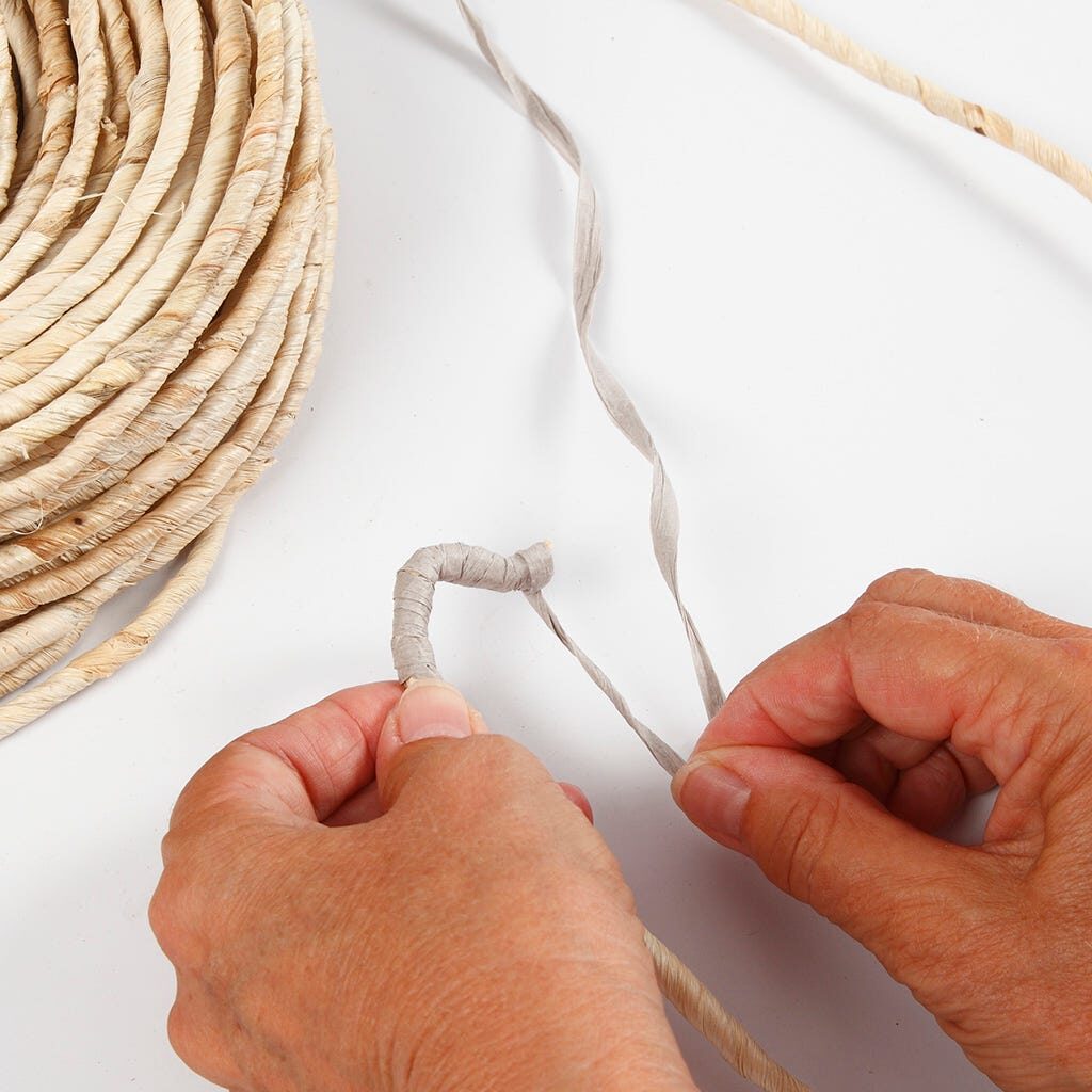 Maisschnur wird mit Papierbast umwickelt